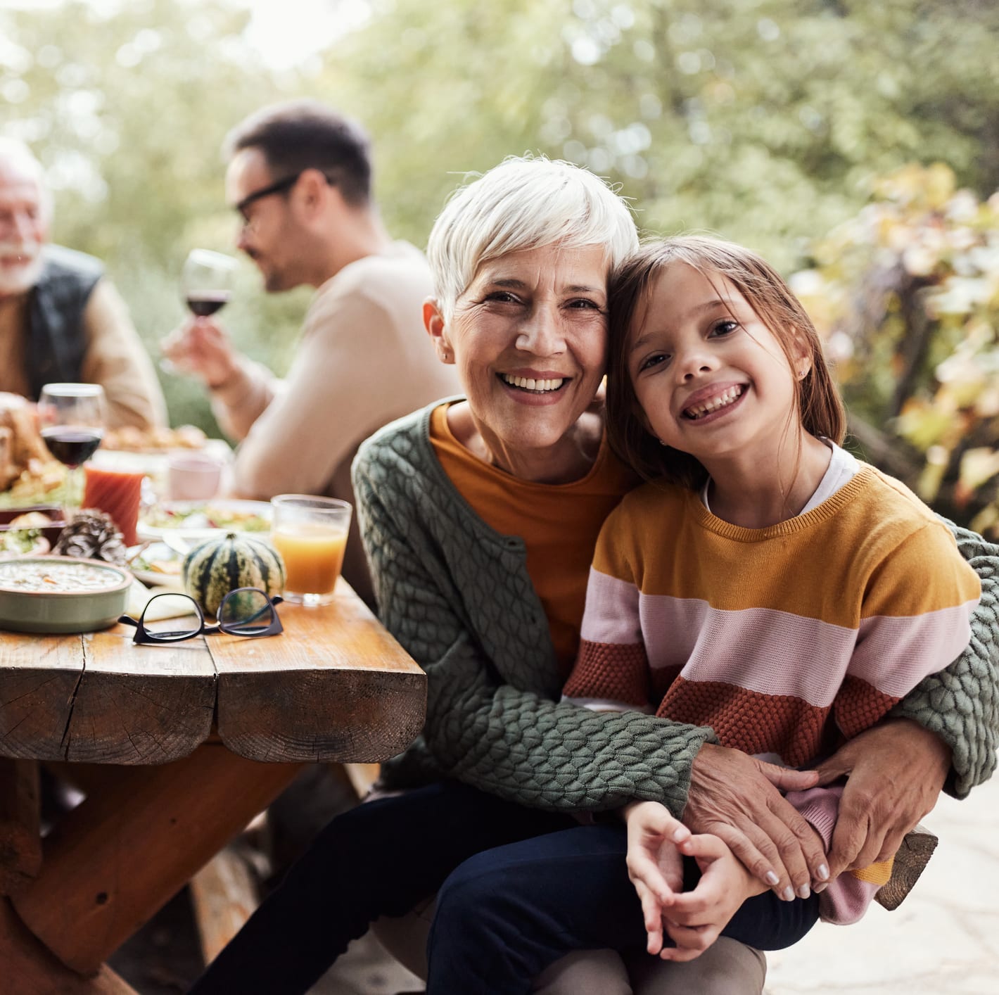 A grandmother and granddaughter embrace at a multi-generation family table, the household Personal Cloud already sits at the center of