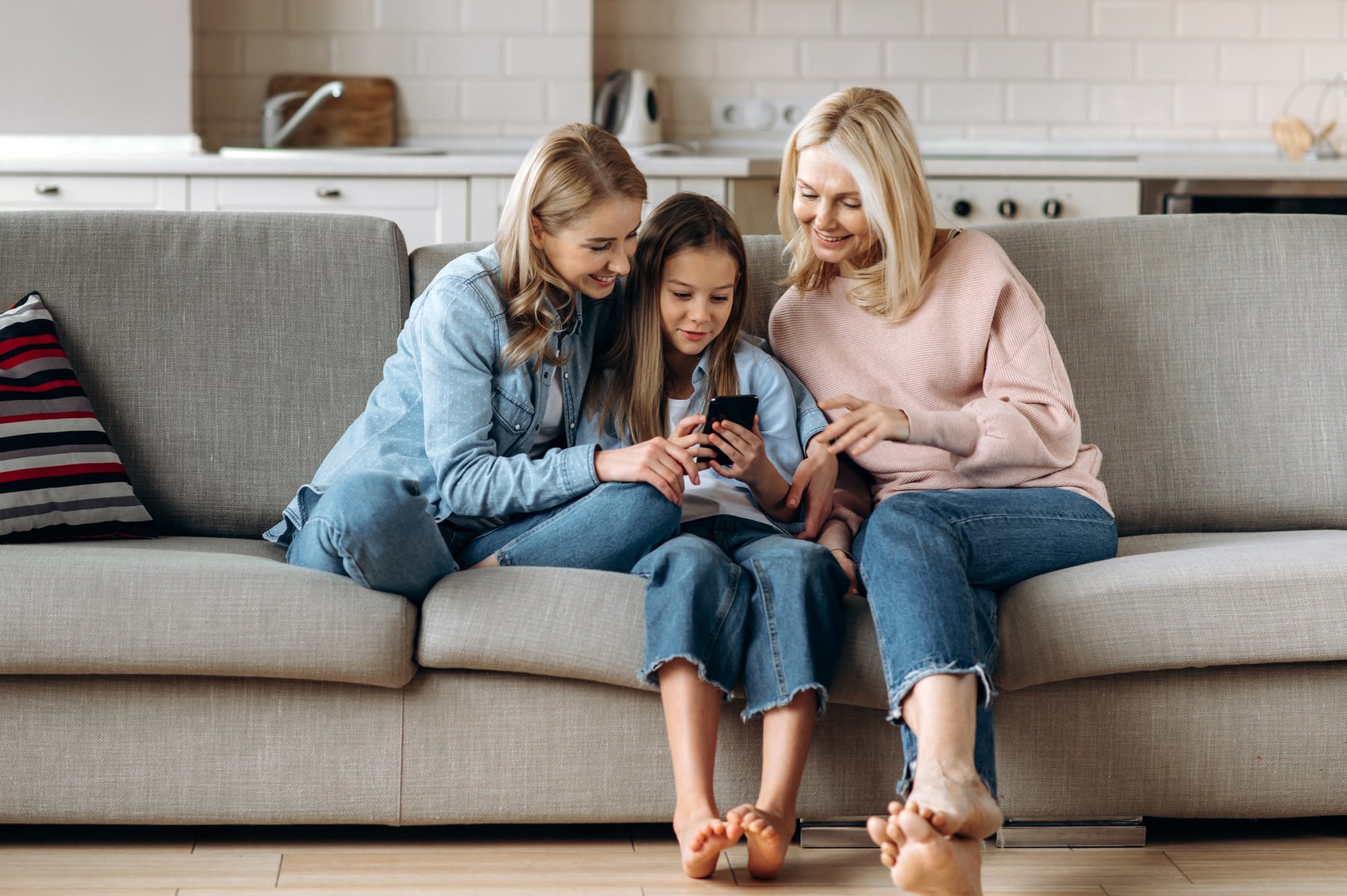 Three generations of one family laughing together on the couch at home