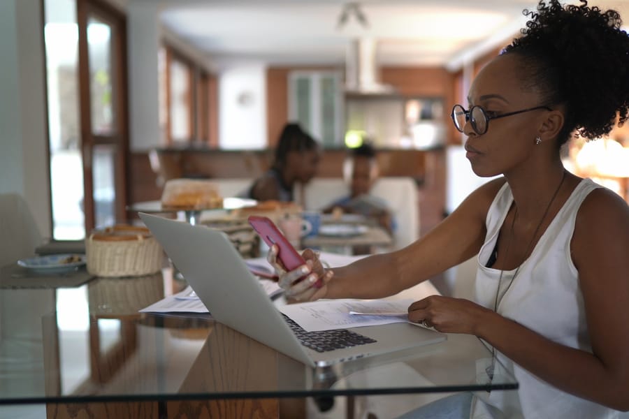 A woman working through documents on a laptop with her phone beside her