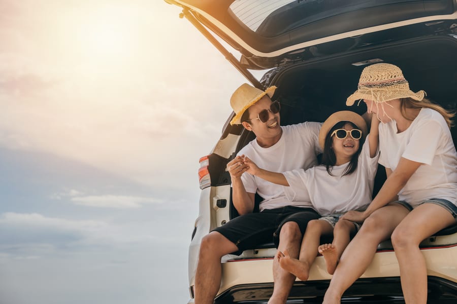 A family sitting in the open boot of a car