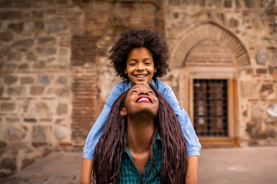 A mother carrying her daughter on her shoulders