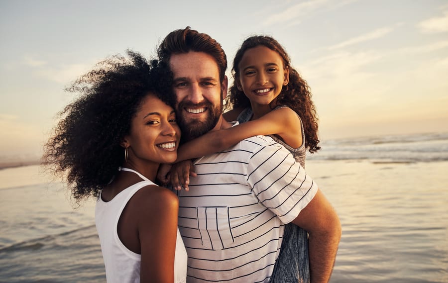 A father carrying his daughter on a beach at sunset