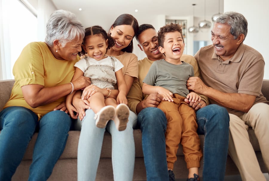 Three generations of a family laughing together on a sofa